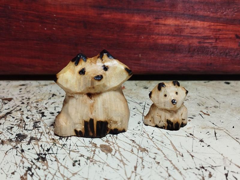 Deux renards en bois. Le plus grand, à gauche, a un regard triste