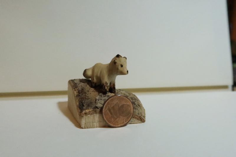 Mini sculpture de renard en bois à côté d'une pièce d'un centime 