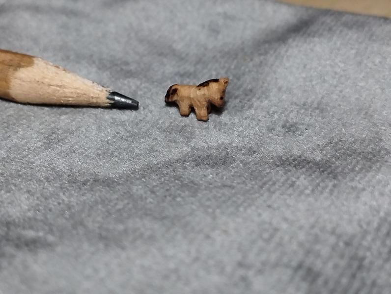 Tout petit cheval en plus bois à côté d'un crayon gris 
