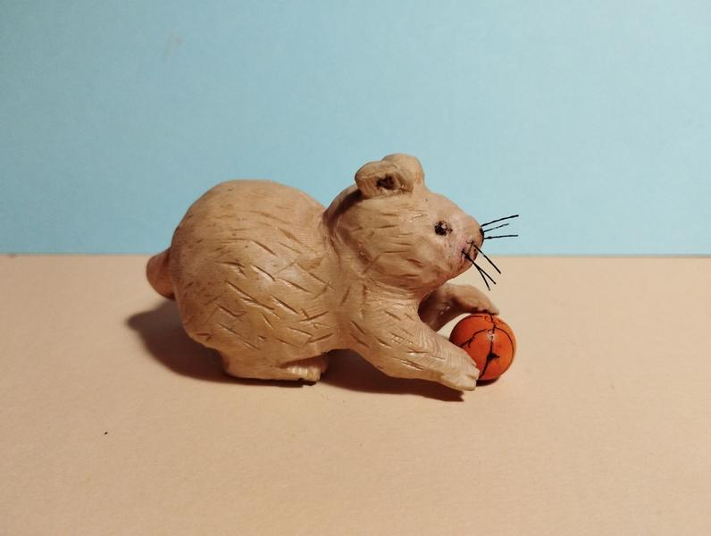 sculpture en bois d'un rat qui tient un ballon de basket