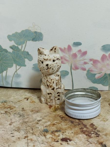 Un chat tigré en bois et une gamelle d'eau