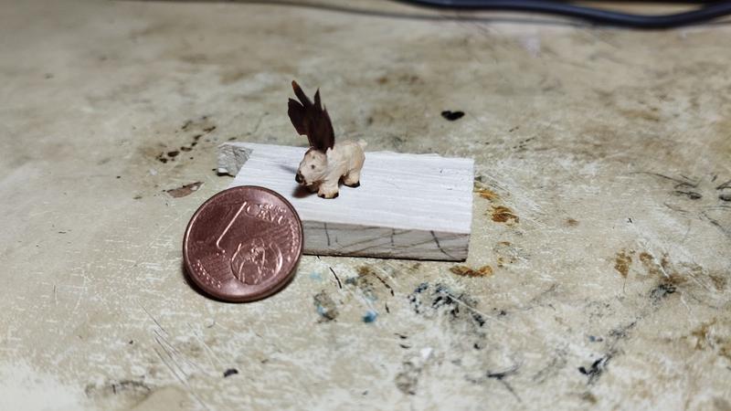 Un mini élan en bois regardant une pièce d'un centime 
