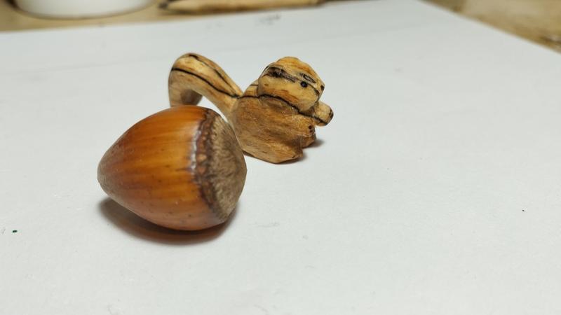 Petit écureuil en bois derrière une noisette 