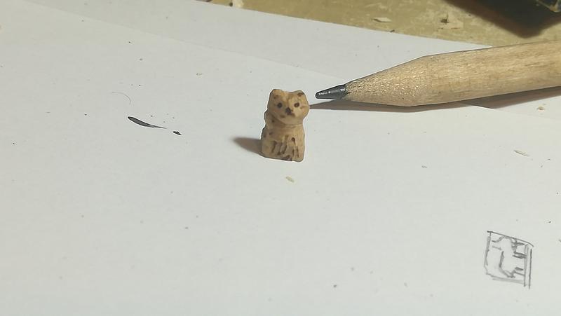 petite sculpture de chat à côté d'un crayon