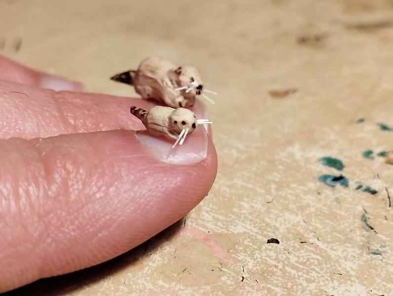 Deux mini ragondins en bois. Ils sont posés sur mes ongles