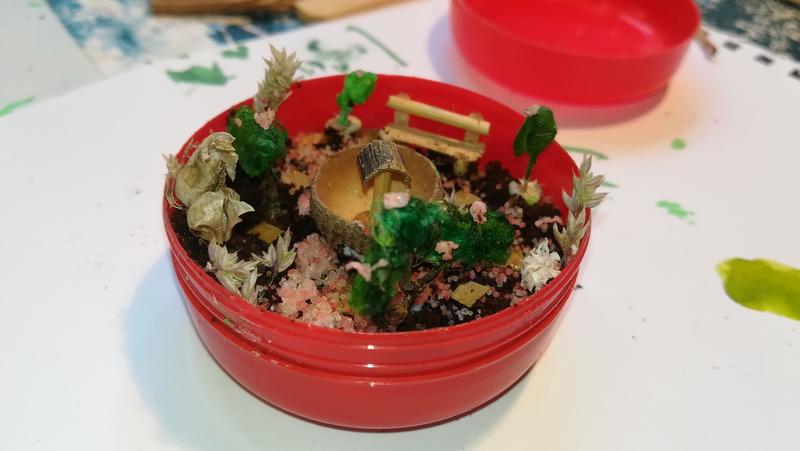 Mini jardin dans une boîte cylindriqueIl y a un banc et des arbustes
