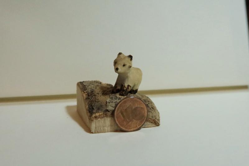 Mini sculpture de renard en bois à côté d'une pièce d'un centime 