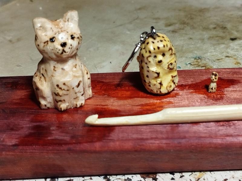 Trois sculptures en bois : un chat tigré, un hérisson, un mini lapin. Il y a aussi un crochet en bambou
