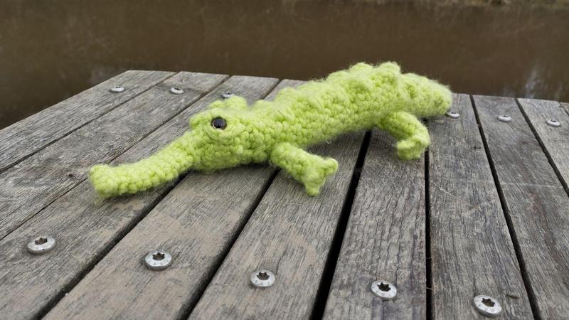 Un gavial fait au crochet. Il est affalé au sol, pattes étendues