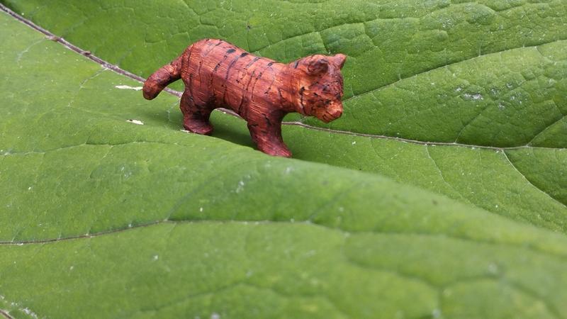 Un tigre en bois rouge posé sur une feuille de rhubarbe