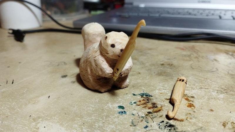Un écureuil en bois qui tient un crochet 