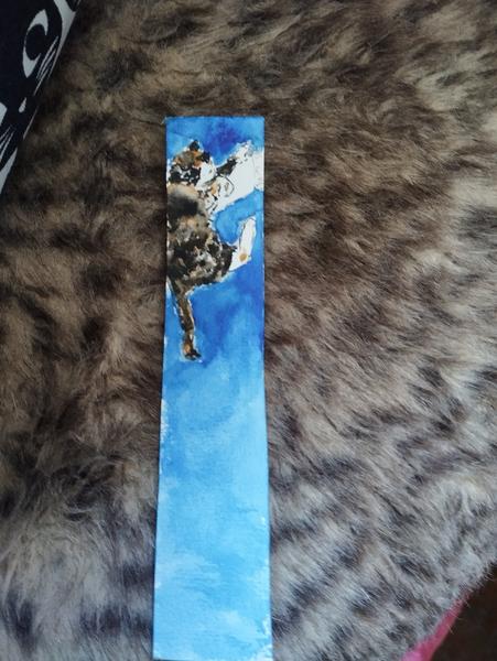 Aquarelle format marque-page d'une chatte tricolore qui dort sur un carnet 