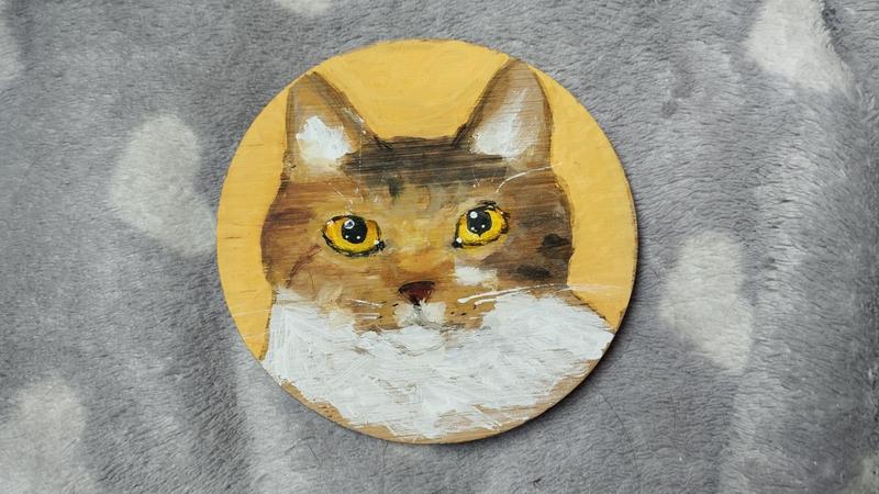 Portrait d'une chatte tigrée marron clair et blanc sur rond de bois 