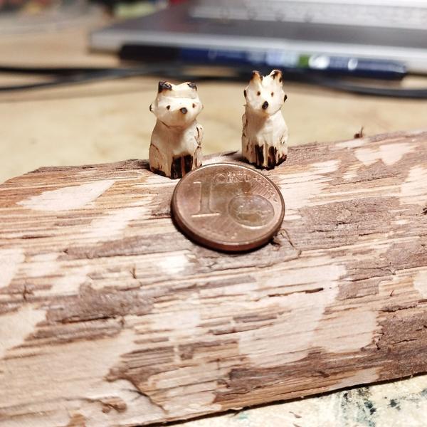 Deux mini renards en bois devant une pièce d'un centime 