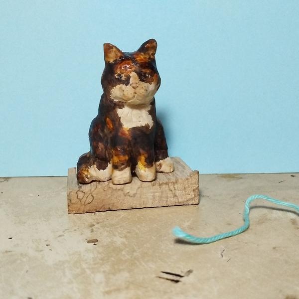 A wood sculpture of a cat, black orange and white