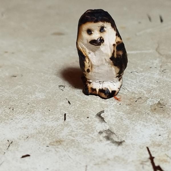 Un manchot en bois. Le plumage est noirci