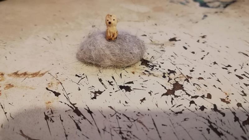 Mini sculpture de chat posée sur un coussin de poils