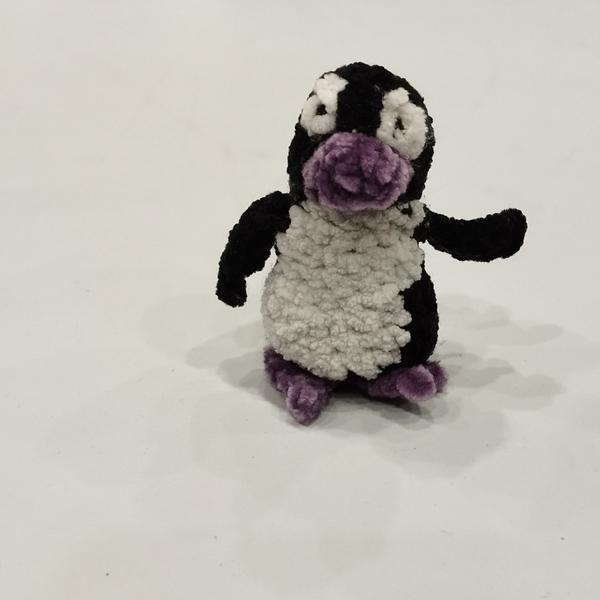 Un petit manchot au crochet. Le corps est noir et blanc, le bec et les pattes violet