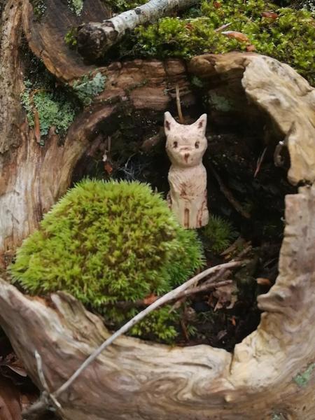 Sculpture de chaton dans le creux d'un tronc recouvert de mousse