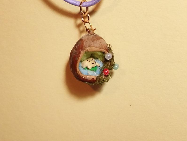 Un pendentif noisette. À l'intérieur, une mini grenouille en bois posée sur un nénuphar 