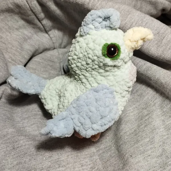 Un oiseau au crochet. Le corps est vert, les ailes et la queue sont bleues