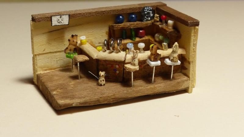Scène miniature représentant un bar. Derrière le comptoir, un renard sert à boire à d'autre renards, des souris et un chat