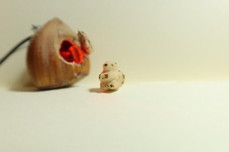 une petite sculpture d'écureuil devant une maison noisette