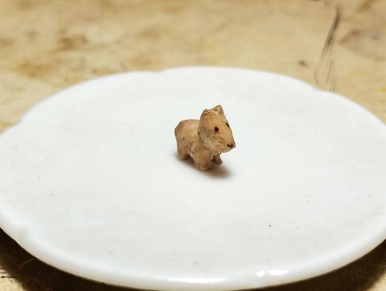 Un petit chien en bois, qui ressemble un peu à un un terrier écossais ou à un bull terrier