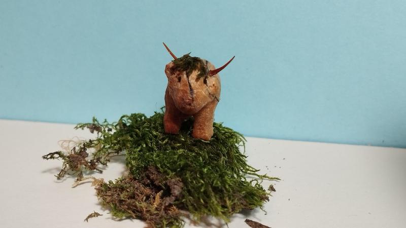 Wood sculpture of a highland cow standing on mossThe fringe is made with moss