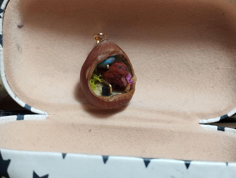 Un pendentif noisette. À l'intérieur un dinosaure fait du crochet