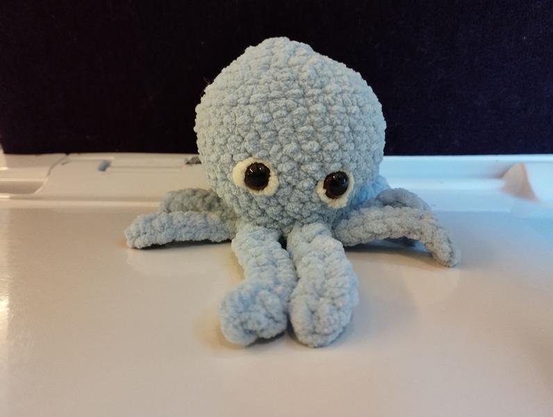 Un poulpe bleu au crochet. Ses yeux sont bordés de jaune 